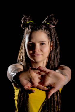 Kendine güvenen genç bir kadın, saç örgüsü ve stüdyo ışıkları altında cesur bir pozla eşsiz tarzını sergiliyor.