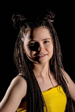 Modayı takip eden genç bir kız dramatik bir stüdyo ortamında sanatsal örgüler ve canlı sarı kıyafetler sergiliyor..