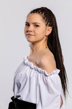 Şık ve kendine güvenen bir kadın omuzlarının üstünde zarif bir şekilde poz verir uzun, örgülü saçlarını güzelce sergiler.