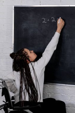 Şık ofisinde, bir kadın yenilikçi fikirlerini karatahtaya yazarken yaratıcı bir şekilde odaklanır.