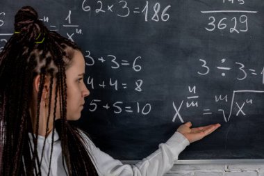 Bir öğrenci, etkileşimli öğrenmeyi teşvik etmek ve anlayışı geliştirmek için matematik denklemlerini tahtada gösteriyor.