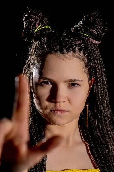 Genç bir kadın, karmaşık örgülü saçlarıyla, özgüven ve yaratıcılığıyla cesur bir poz verir.