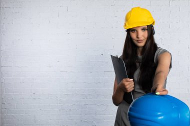 Sert şapkalı kararlı genç bir kadın canlı bir şantiyede güvenliğe olan bağlılığını gösteriyor.