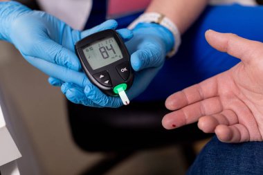 Kendini adamış bir sağlık uzmanı spesifik bir cihaz kullanarak kan glikozu izleme yöntemini gösteriyor.