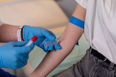 Bir sağlık uzmanı, klinik ortamda bir hastaya kan alma prosedürünü dikkatlice uygular.