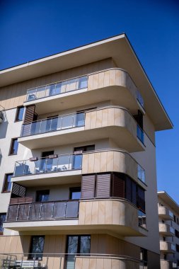 Modern ve çağdaş bir apartman kompleksi zarif balkonları güzel bir mavi gökyüzüne karşı sergiliyor.