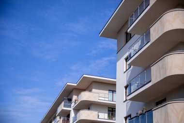 Parlak mavi gökyüzüne karşı balkonları olan şık ve modaya uygun apartmanlar canlı bir şehir yaşam tarzı sağlıyor.