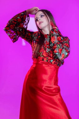 Şık ve modaya uygun bir model zarif bir şekilde parlak pembe bir arka plana karşı çarpıcı bir kıyafet sergiliyor.