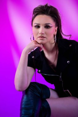 Çağdaş moda alanında çarpıcı derecede güzel bir model renkli ve canlı bir arkaplana karşı zarif bir poz veriyor.