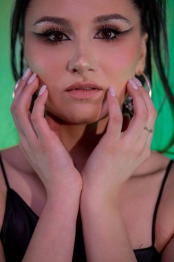 Çarpıcı bir portre, canlı ve dinamik bir arkaplan karşısında cesur bir makyaj ve anlamlı bir stil içeriyor.