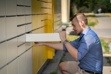 Şık bir genç adam mektuplarını modern ve çağdaş bir posta kutusundan alıyor.