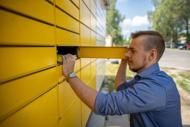 Parlak, neşeli, sarı bir posta kutusuyla meşgul olan genç bir adam şehir merkezinde bir yerde.