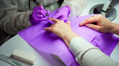 Bir teknisyen, kuaförde rahatlatıcı bir manikür seansı sırasında müşterilerin tırnaklarına güzel tırnak resimleri çizer.