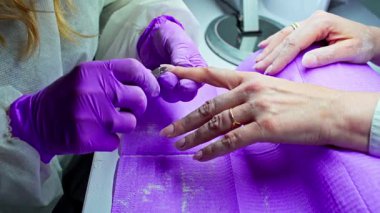 Modern bir kuaförde, yetenekli bir tırnak teknisyeni detaylı tırnak sanatını her müşteriye özen ve özenle uygular.