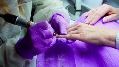 Yetenekli bir tırnak teknisyeni, modern bir kuaförde, olağanüstü bir sanat sergileyen bir matkapla ayrıntılı tırnak sanatı yapıyor.