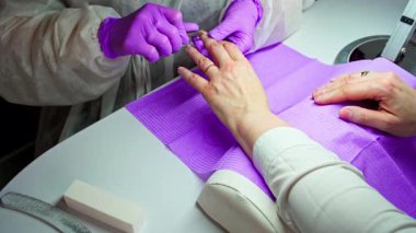 Modern bir kuaför salonunda uzman bir tırnak bakımını teslim eden yetenekli bir tırnak teknisyeninin detaylı bir yakın çekimi.