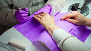 Yetenekli bir tırnak teknisyeni manikür sırasında jöle sürerek müşteri memnuniyeti ve cilalı bir görünüm sağlar.