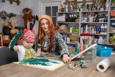 Yaratıcı bir stüdyoda, coşkulu çocuğuna canlı bir sanat projesinde rehberlik eden bir anne olarak besleyici bir an.