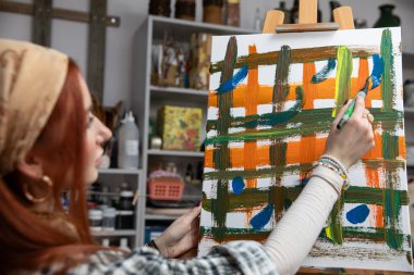 Bir sanatçı, samimi ve ilham verici stüdyo alanındaki soyut bir resme canlı ve canlı renkler katar.