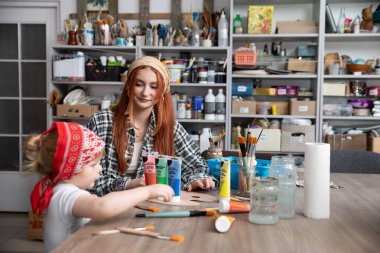 Canlı bir stüdyoda, bir çocuk ve bir yetişkinin yaratıcı aktivitelerle meşgul olduğu neşeli bir sanat seansı..