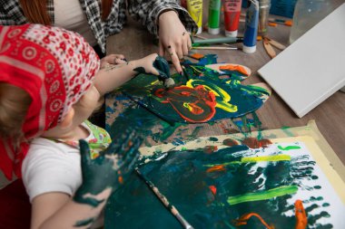 Neşeli ve renkli bir deneyim, bir çocuk coşkuyla canlı renkler ve parmaklarıyla resim yaparken başlar.