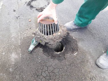 Çalışkan bir işçi, düzgün su akışı ve devam eden bakımı sağlamak için kanalizasyondan enkazı dikkatlice kaldırır.