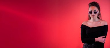 Kendine güvenen bir model canlı kırmızı bir arka plana karşı duruyor, son moda eğilimlerini gözler önüne seriyor.