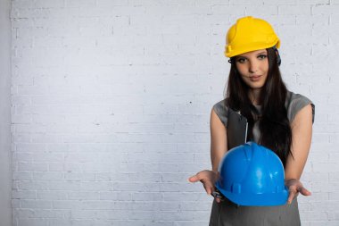 Profesyonel bir kadın, güvenlik ve sorumluluğu vurgulayan modern bir ortamda inşaat kasklarını gururla sergiliyor.