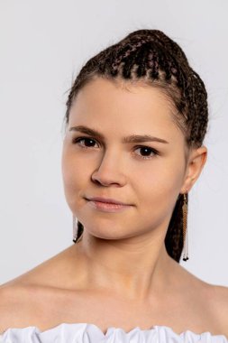 Saçı örgülü, doğal güzelliğini ve zarafetini sergileyen bir kadının yakın plan portresi..