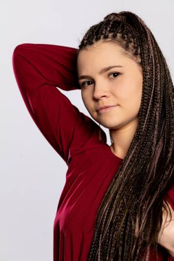 Kendinden emin ve kendinden emin genç bir kadın şık örgülü saç stilini gururla sergiliyor.