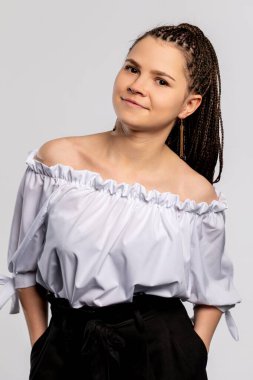 Kendinden emin genç bir kadın, modaya uygun bir şekilde omuzlarının üstünde poz veriyor, neşeli bir ifade sergiliyor.