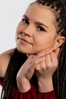 Güzel örülmüş saçları olan zarif genç bir kadın zarif ve çarpıcı özelliklerini sergiliyor.