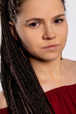 Genç bir kadının yakından çekilmiş görüntüsü. Saçlarını karmakarışık örüyor ve güçlü, kendinden emin bir ifade sergiliyor.