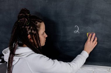 Bir kişi, devam eden yaratıcılık, eğitim ve aktif öğrenme karışımını gösteren bir yazı tahtasını siler