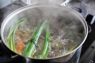 Bir tencere taze sebze kaynıyor, buhar ve kabarcıklar yaratıyor, besleyici yemeklerin önemini vurguluyor.