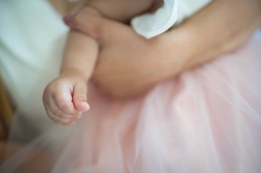 Küçük bir bebek narin küçük el yumuşak pembe tül kumaş katmanlarının içine yerleştirilmiş sıcak bir kucaklaşmada dinleniyor.