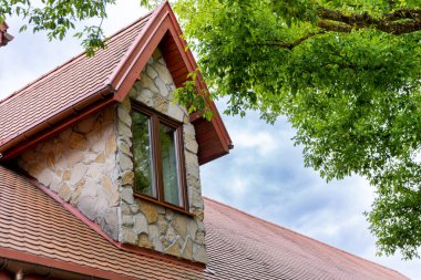 Çok güzel taş duvarları ve eğimli çatısı olan canlı yeşilliklerle çevrili güzel ve büyüleyici bir kır evi.