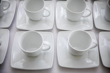 Beyaz kahve fincanlarının modern yemek için ideal kare tabaklar üzerine mükemmel bir minimalist düzenleme.