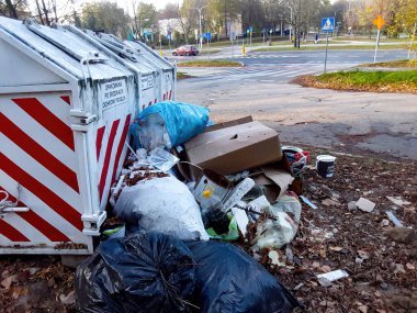 Kentsel alanda işlek bir kavşağın yakınında çeşitli çöp türleriyle dolu bir çöp kutusu