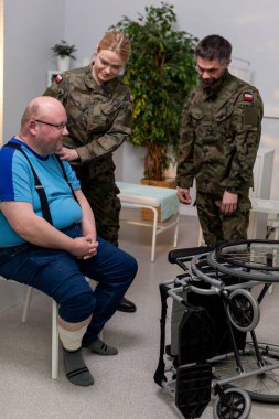 Askerler, klinik ortamda ileri düzeyde rehabilitasyon ekipmanları kullanarak bir hastaya destek sağlıyorlar.
