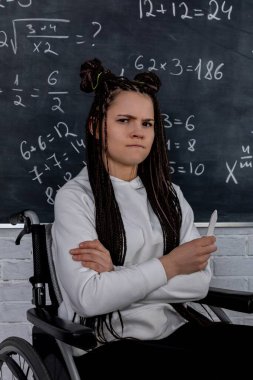 Tekerlekli sandalyedeki kararlı, kendinden emin bir öğrenci hayat dolu bir sınıfta olağanüstü bir zeka gösteriyor.