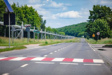 Göze çarpan bir hız tümseği, bilgilendirici işaretler ve yemyeşil bir çevreye sahip huzurlu, sakin bir kırsal yol.
