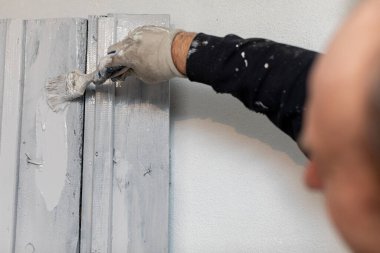 Yetenekli bir ressam, ustalık ve ustalık için fırça ve eldiven kullanarak bir duvarı dikkatlice bitiriyor.