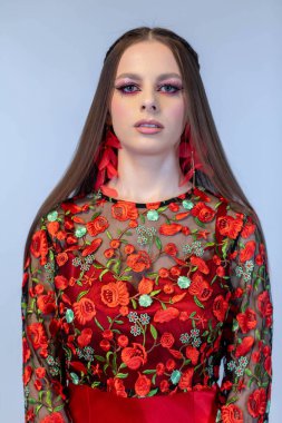 Zarif genç bir kadın kendine güvenerek poz veriyor. Güzel, canlı bir çiçekli elbise, büyüleyici bir makyajla eşleştirilmiş.