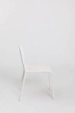 Çok yönlü ev dekorasyonu için temiz ve parlak beyaz bir zemin üzerine zarif ve modern bir beyaz sandalye.