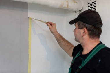 Çok yetenekli profesyonel bir ressam, kusursuz ve pürüzsüz bir boyayı tamamlamak için duvarı dikkatlice bantlıyor.