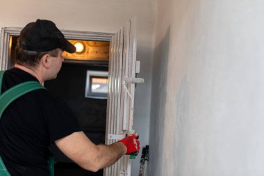 Yetenekli bir işçi, yenileme projesinde çeşitli temel görevlere hazırlanırken düzenli olarak merdiveni ayarlar.