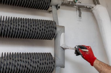 Endüstriyel bir çalışma ortamında metal boruları tekerlekli fırçayla titizlikle boyayan yetenekli bir işçi.