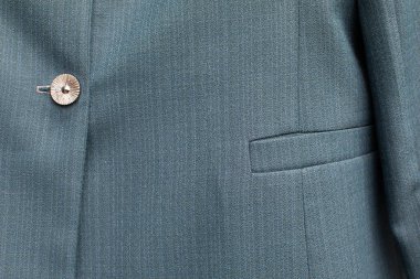 Entellektüel bir ceketin karmaşık bir yakın çekim görüntüsü eşsiz dokularını ve şık bir düğmesini gözler önüne seriyor.