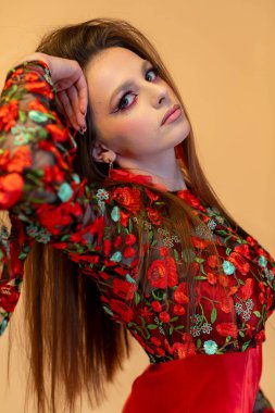 Göz kamaştırıcı bir manken zarif ve zarif poz verir canlı bir çiçek desenli bluzla zengin renklerle süslenir